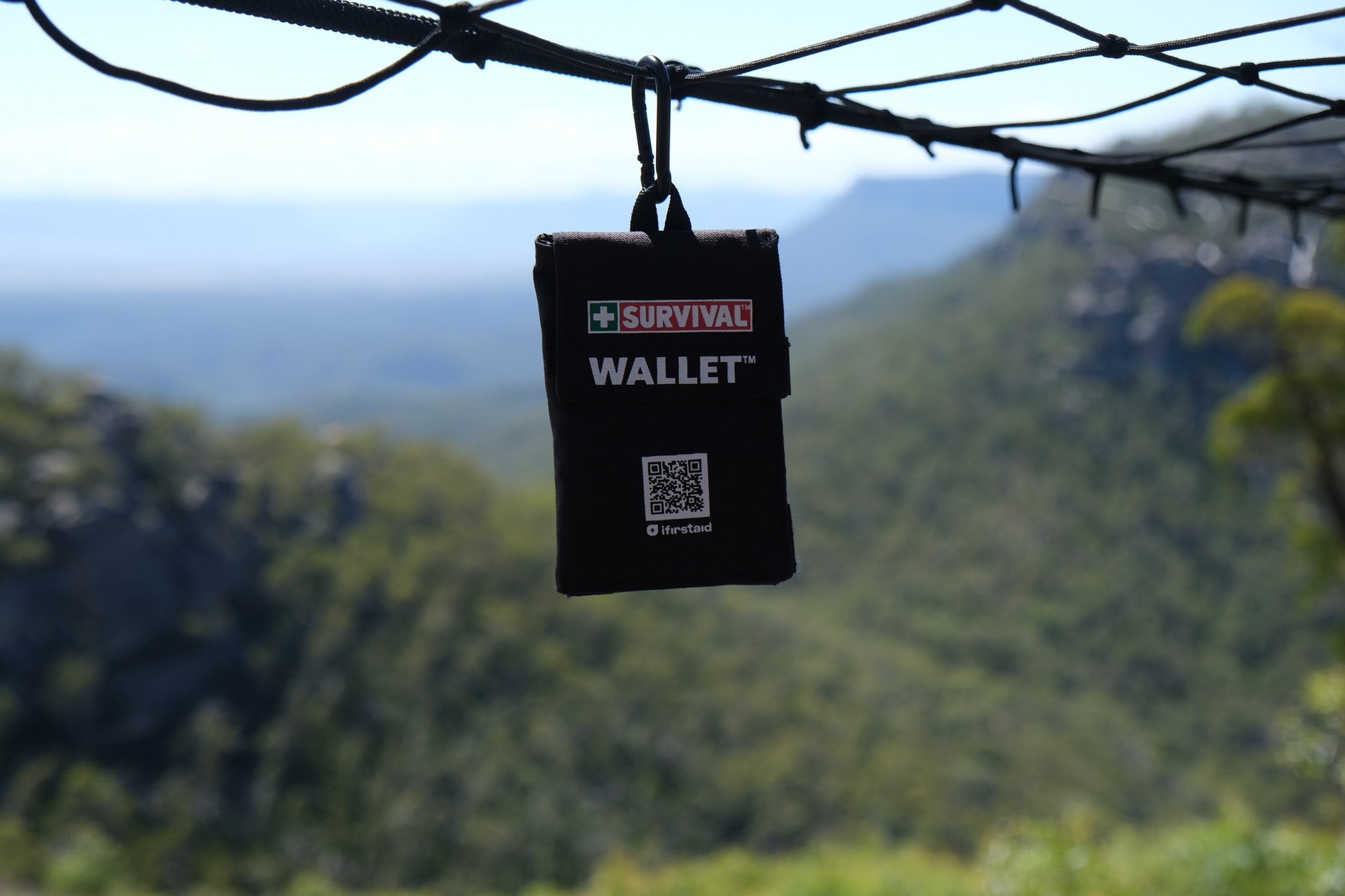 Black Wallet 2.0 hanging from a line with a mountain valley behind it