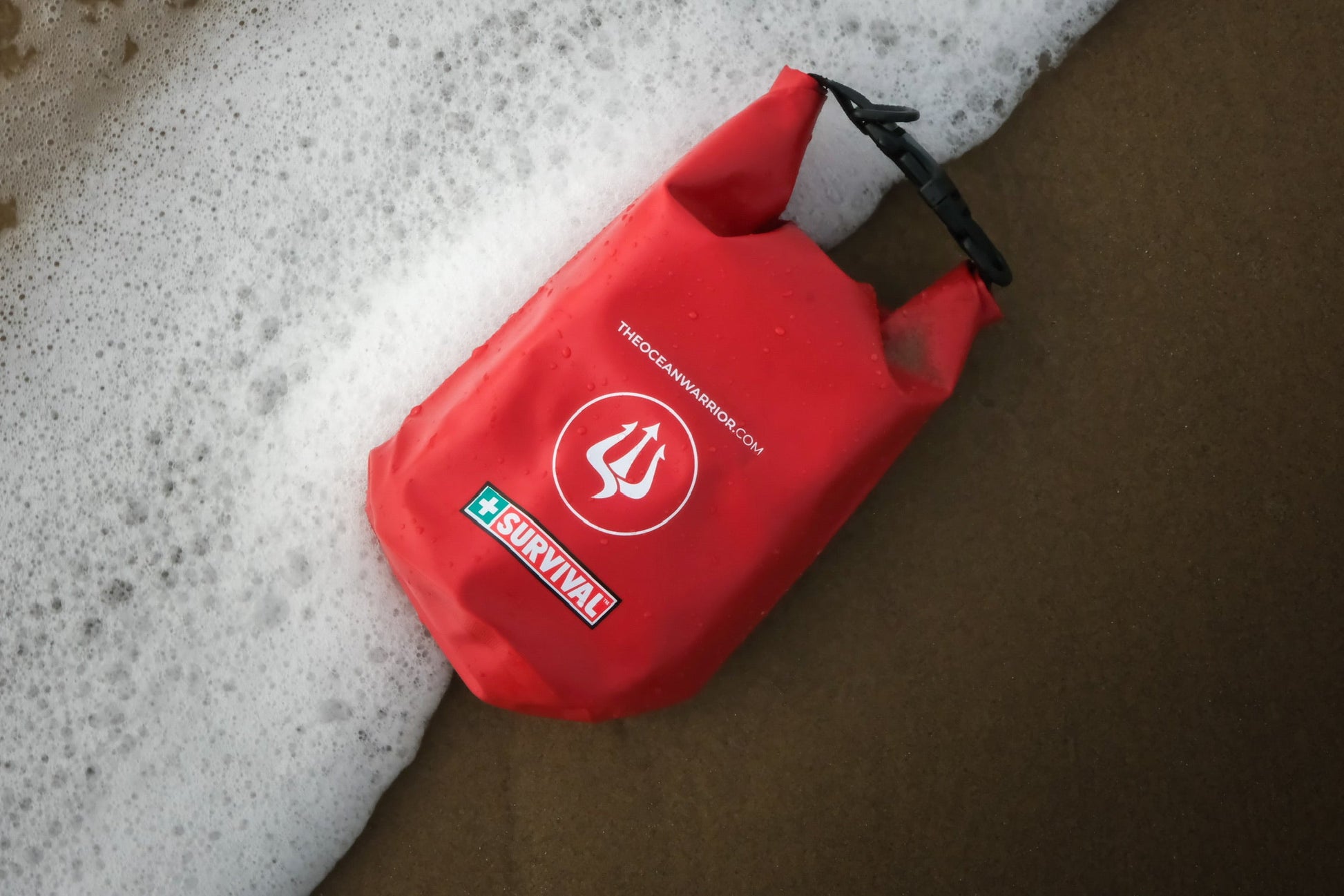 Red dry bag lying in the surf on wet sand