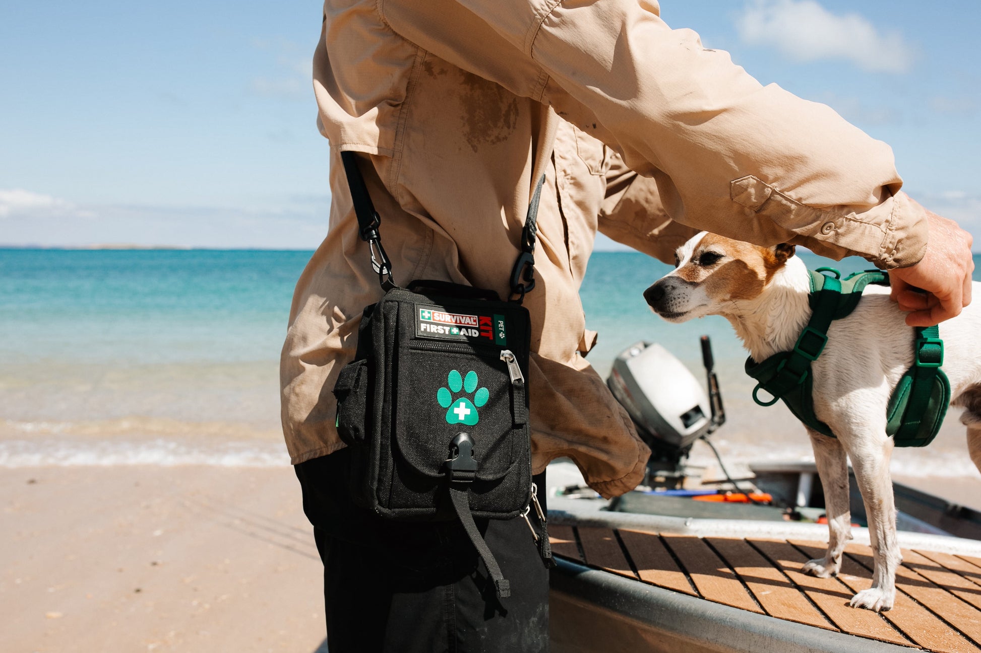 Dog on a boat beside a person wearing the Pet first aid bag