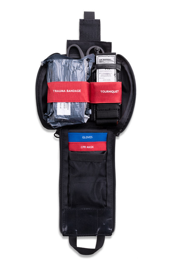 Trauma pouch opened, showing the tourniquet, trauma dressing and gloves