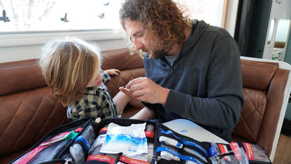 Parent treating a child's hand at home with the opened case beside them